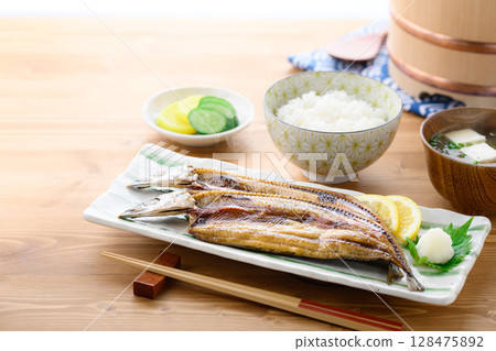 Steaming Japanese breakfast: Grilled fish (filleted saury), rice and miso soup on a table 128475892