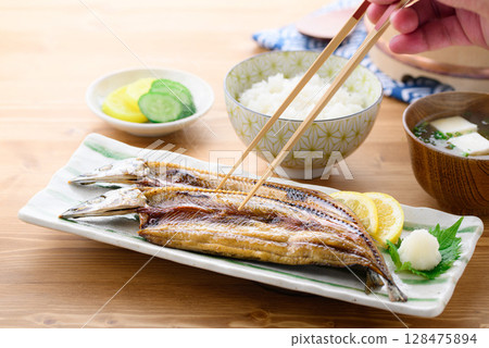 熱騰騰的日式早餐：桌上的烤魚（秋刀魚片）、米飯和味噌湯 128475894