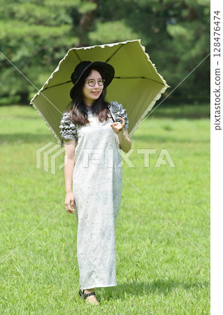 走與遮陽傘的一位小姐 128476474