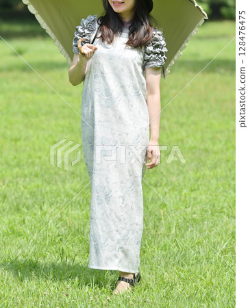 A young lady walking with a parasol 128476475