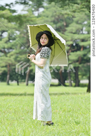 A young lady walking with a parasol A young lady walking with a parasol 128476480