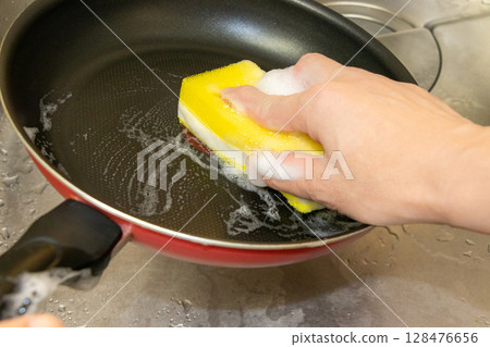 用浸有清潔劑的海綿清洗鍋具 128476656