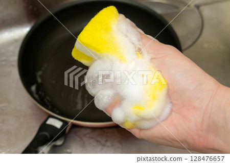 將清潔劑浸泡在廚房海綿中，搓揉起泡 128476657
