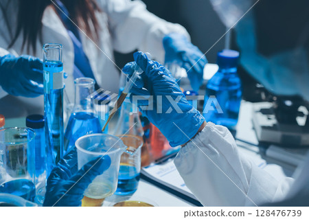 Scientist pipetting medical samples into microplate in laboratory 128476739