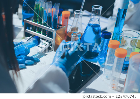 Scientist pipetting medical samples into microplate in laboratory 128476743