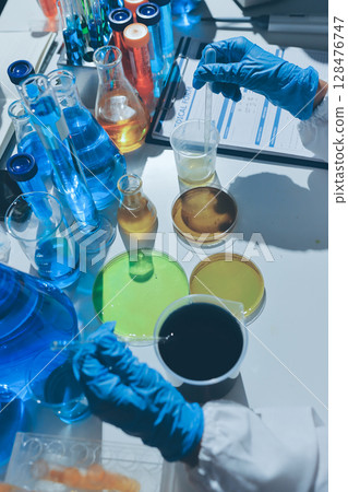 Scientist pipetting medical samples into microplate in laboratory 128476747