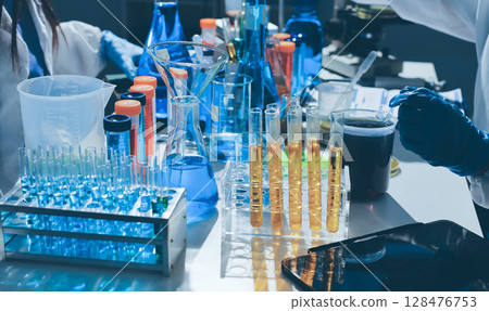 Scientist pipetting medical samples into microplate in laboratory 128476753