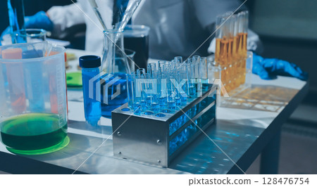 Scientist pipetting medical samples into microplate in laboratory 128476754