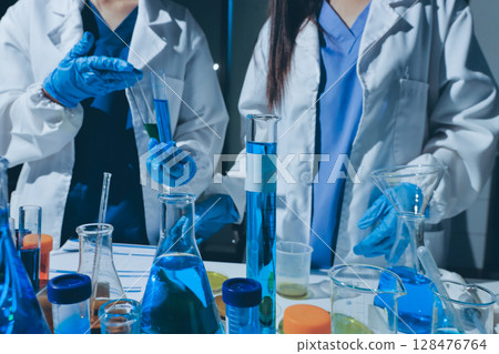 Scientist pipetting medical samples into microplate in laboratory 128476764