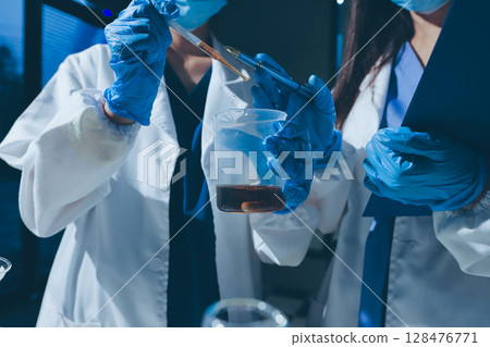 Scientist pipetting medical samples into microplate in laboratory 128476771