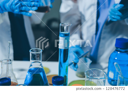 Scientist pipetting medical samples into microplate in laboratory 128476772