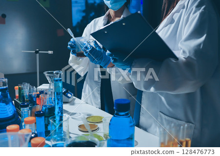 Scientist pipetting medical samples into microplate in laboratory Scientist pipetting medical samples into microplate in laboratory 128476773