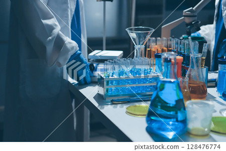 Scientist pipetting medical samples into microplate in laboratory 128476774