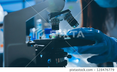 Scientist pipetting medical samples into microplate in laboratory 128476779