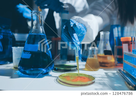 Scientist pipetting medical samples into microplate in laboratory 128476786