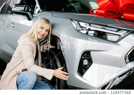 Woman checking new car tires in a dealership 128477168