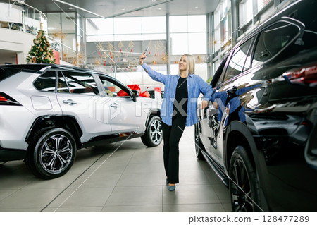 Customer taking selfie with new car in dealership 128477289