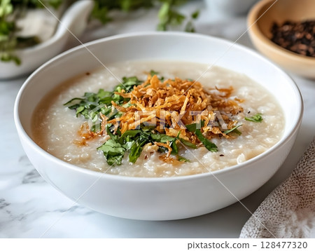 Indonesian chicken congee or rice porridge with shredded chicken meat served with some condiments such as chopped scallion, celery and crispy fried shallot. Indonesian chicken congee or rice porridge with shredded chicken meat served with some condiments such as chopped scallion, celery and crispy fried shallot. 128477320
