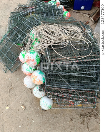 Pile of Fishing Traps with Buoys on Sandy Ground. Pile of Fishing Traps with Buoys on Sandy Ground. 128477560