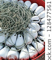 Fishing Buoys and Rope Close-up of a red tub filled with white buoys and tangled rope. 128477561