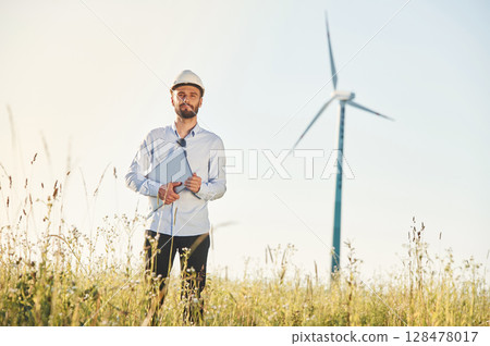 Working by using laptop. Service engineer is on the field with windmills 128478017