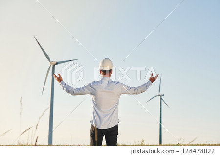 Conception of success and freedom. Service engineer is on the field with windmills Conception of success and freedom. Service engineer is on the field with windmills 128478022