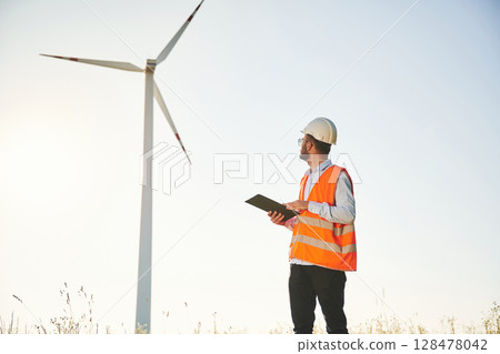 In sunglasses, with notepad. Service engineer is on the field with windmills 128478042