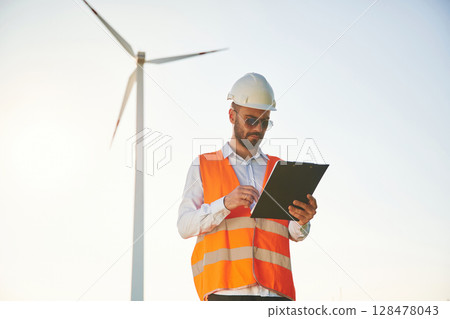 In sunglasses, with notepad. Service engineer is on the field with windmills 128478043
