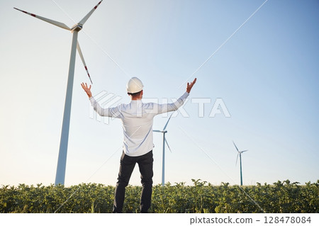Conception of success and freedom. Service engineer is on the field with windmills Conception of success and freedom. Service engineer is on the field with windmills 128478084