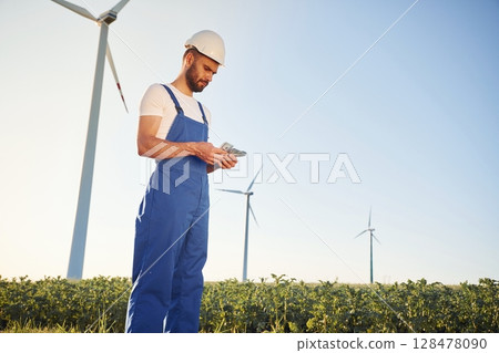 Counting the money. Service engineer is on the field with windmills 128478090