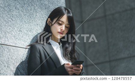 A business scene where a woman checks her schedule on her smartphone 128478557