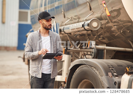 Using tablet. Young truck driver in casual clothes Using tablet. Young truck driver in casual clothes 128478685