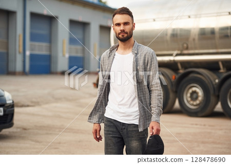 Against vehicle. Young truck driver in casual clothes 128478690