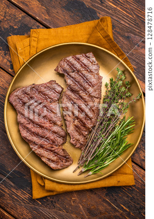 Juicy Denver, chuck eye steak, expertly grilled to perfection, offering a mouthwatering aroma and a deliciously charred exterior. wooden background. top view Juicy Denver, chuck eye steak, expertly grilled to perfection, offering a mouthwatering aroma and a deliciously charred exterior. wooden background. top view 128478716