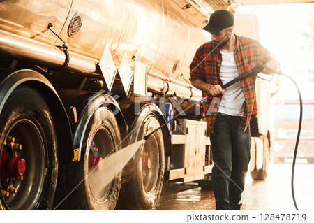 Washing the vehicle. Young truck driver in casual clothes Washing the vehicle. Young truck driver in casual clothes 128478719