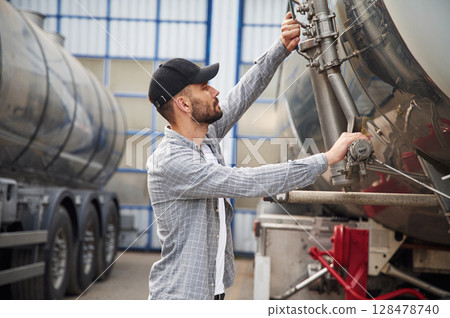 Between two vehicles. Young truck driver in casual clothes Between two vehicles. Young truck driver in casual clothes 128478740