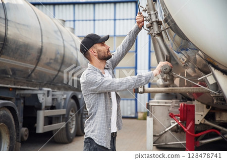 Between two vehicles. Young truck driver in casual clothes Between two vehicles. Young truck driver in casual clothes 128478741