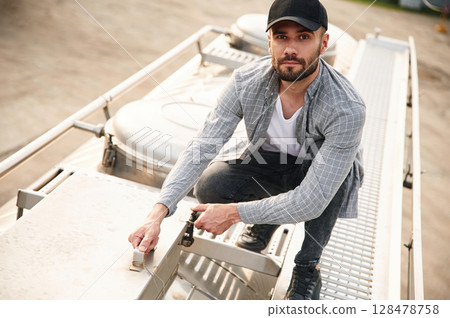 On the top of fuel tanker. Young truck driver in casual clothes 128478758