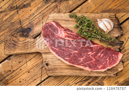 Raw rump cap steak, uncooked beef meat, showcasing its rich marbling and vibrant color. wooden background. top view 128478787