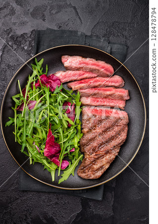 Succulent Denver cut, showcasing a perfect sear and rich color after grilling. black background. top view 128478794