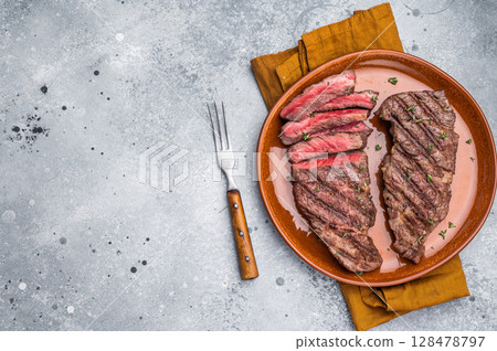 Tender flat iron steak, grilled to enhance its natural flavors and tenderness. grey background. top view 128478797