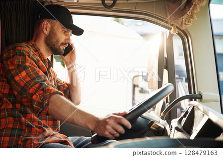 Talking by phone. Young truck driver in casual clothes Talking by phone. Young truck driver in casual clothes 128479163