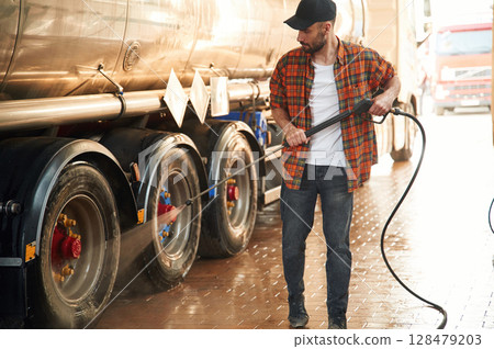 Walking and washing the vehicle. Young truck driver in casual clothes Walking and washing the vehicle. Young truck driver in casual clothes 128479203
