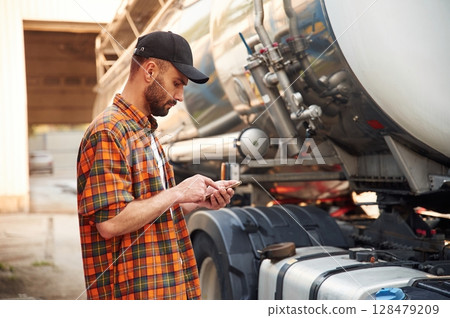 Holding smartphone. Young truck driver in casual clothes Holding smartphone. Young truck driver in casual clothes 128479209