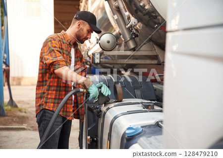 Holding refueling device. Young truck driver in casual clothes Holding refueling device. Young truck driver in casual clothes 128479210
