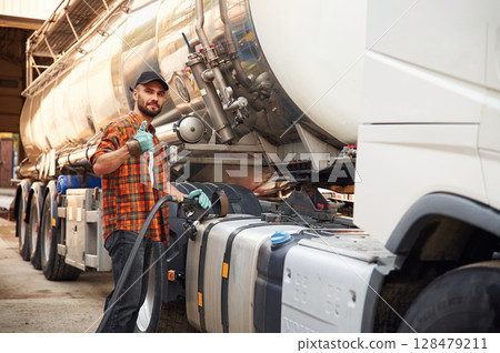 Holding refueling device. Young truck driver in casual clothes Holding refueling device. Young truck driver in casual clothes 128479211