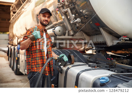 Young truck driver in casual clothes is refueling the vehicle Young truck driver in casual clothes is refueling the vehicle 128479212