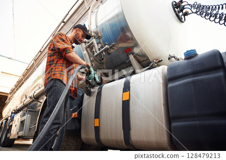 Young truck driver in casual clothes is refueling the vehicle Young truck driver in casual clothes is refueling the vehicle 128479213