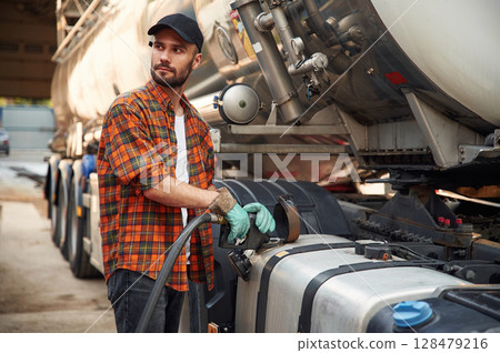 Young truck driver in casual clothes is refueling the vehicle 128479216