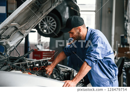 Adjusting the screws. Auto mechanic working in garage. Repair service 128479754